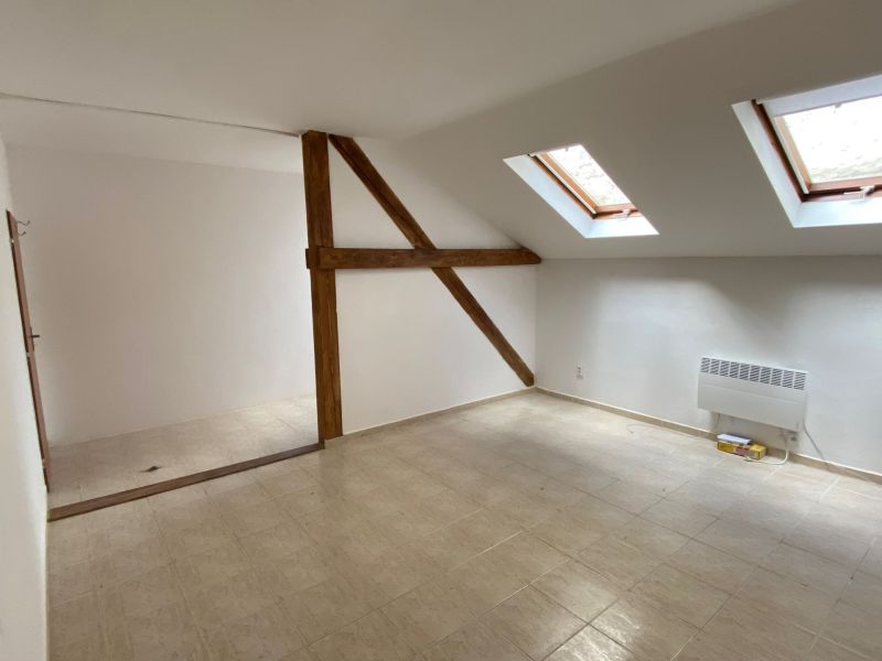 Attic office with ceramic floor and skylights, wooden beam.