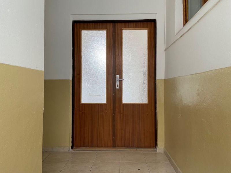 In the offices, there are double doors with glazing and light brown walls.