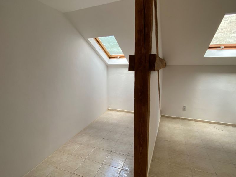 Attic office space with a wooden beam and skylights.