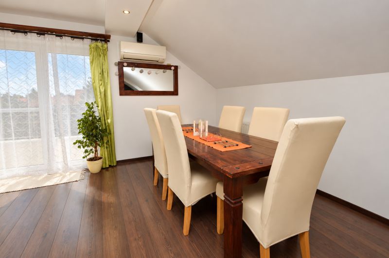 Dining room in a family house with a wooden decor floor and large windows.