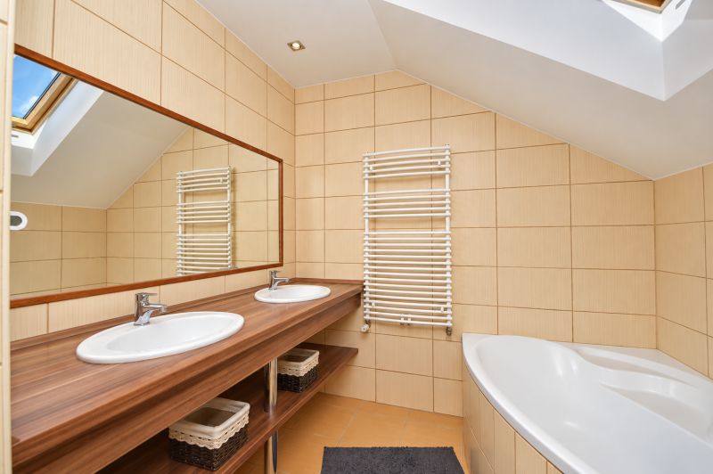 A bathroom with a double sink, mirror, and bathtub in the attic of a family house.