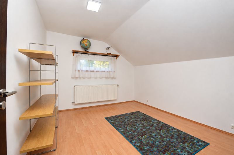 A room in a family house with a floor featuring a wooden decor, a shelf, and a window.
