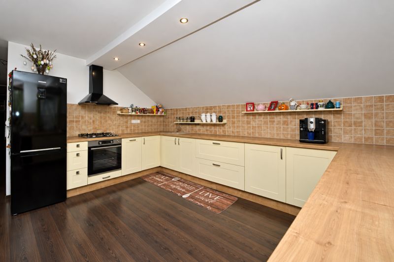 A kitchen in a family house with a wooden decor floor and cream cabinets.