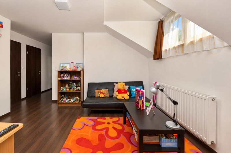 Children's room with wooden decor flooring, toys, and a sofa in a family house.