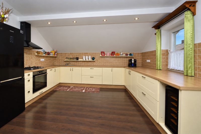 A spacious kitchen in a family house with a wooden decor floor and light furniture.