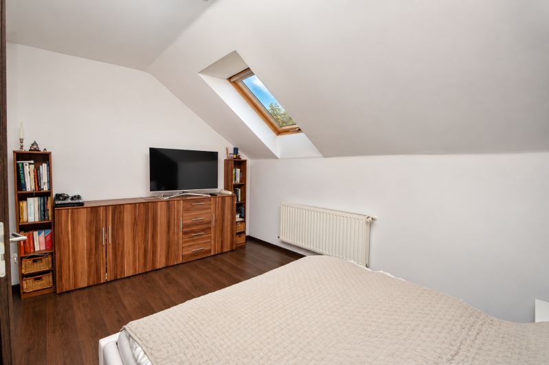 Attic bedroom with wood-patterned flooring in a family house.