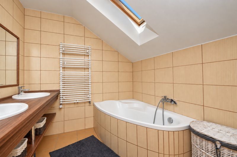 Attic bathroom with a bathtub, double sink, and skylight in a family house.