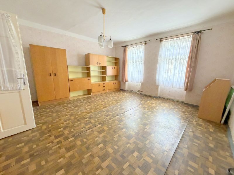 Spacious living room in a family house with built-in wardrobes and a wooden decor floor.