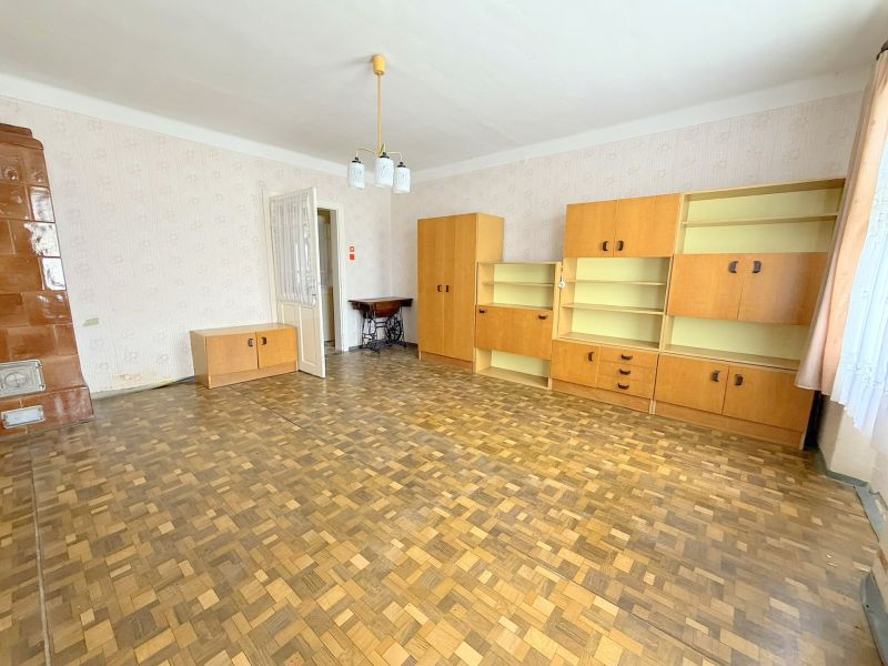 Living room with wood-patterned flooring, light furniture, and a wood-burning stove in a family house.