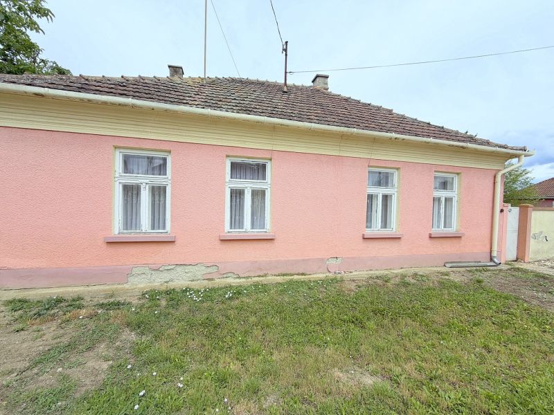 A family house in Dunakiliti with a pink facade and four windows on the ground floor.