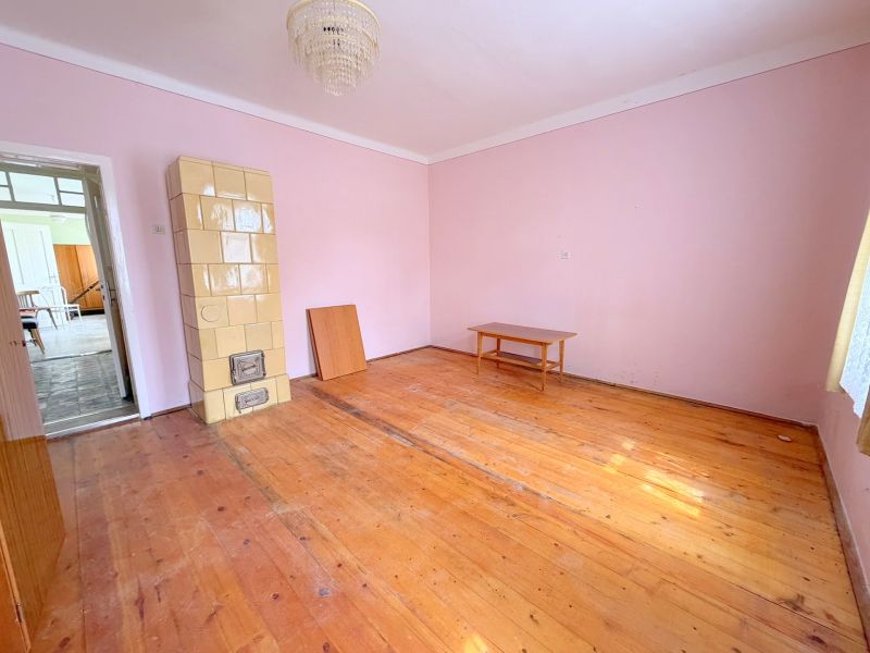 A room in a family house with a tiled stove and a floor with a wooden decor.