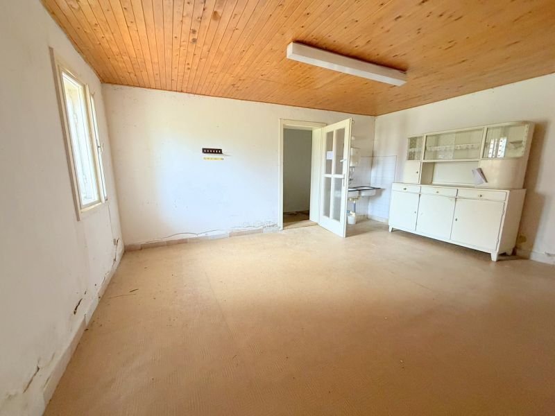The interior of a family house with a wooden ceiling, old furniture, and white walls.