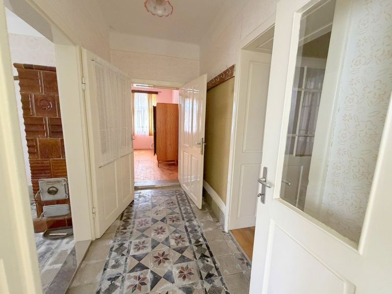 A hallway with a tiled stove and flooring in a family house.