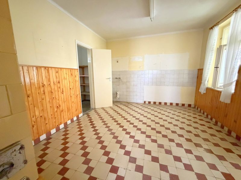 A kitchen in a family house with tiles and wooden wall cladding.