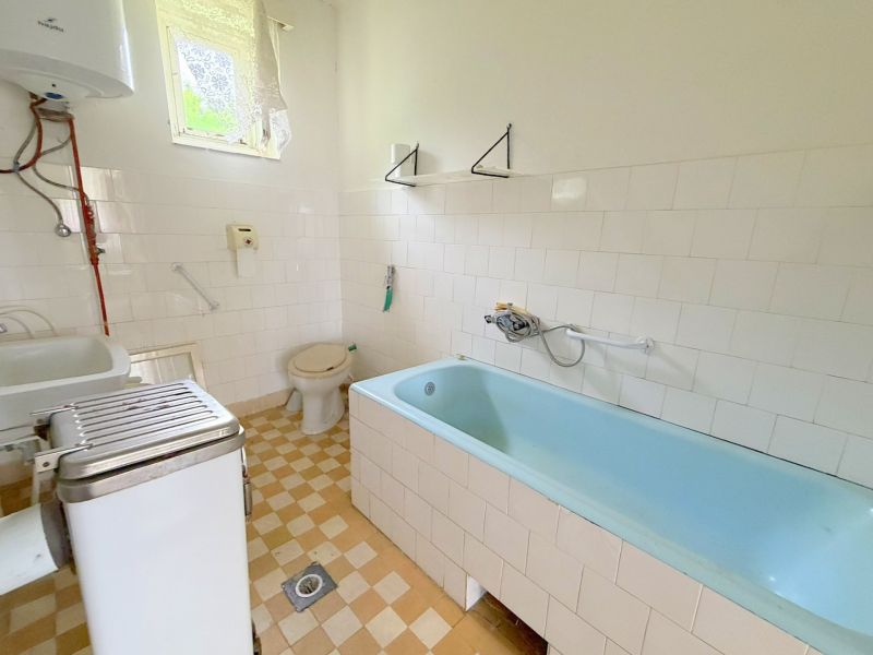 Bathroom with a bathtub and tiles in a family house with simple furnishings.