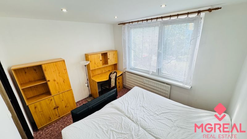 A bedroom in a 3-room apartment with wooden furniture and a large window.