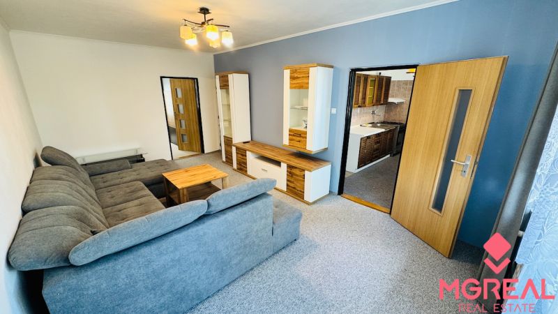 Living room with a gray sofa and furniture in a 3-room apartment, floor with wood decor.