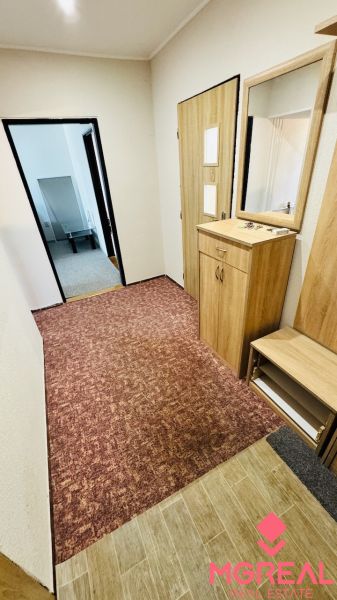 A hallway with furniture and carpet in a 3-room apartment with a wooden decor floor.