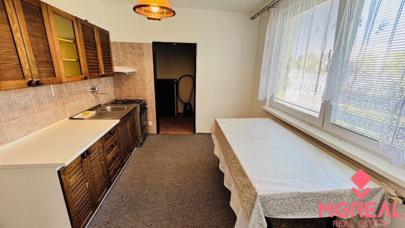 A kitchen in a 3-room apartment with light walls, wooden cabinets, and a dining table.