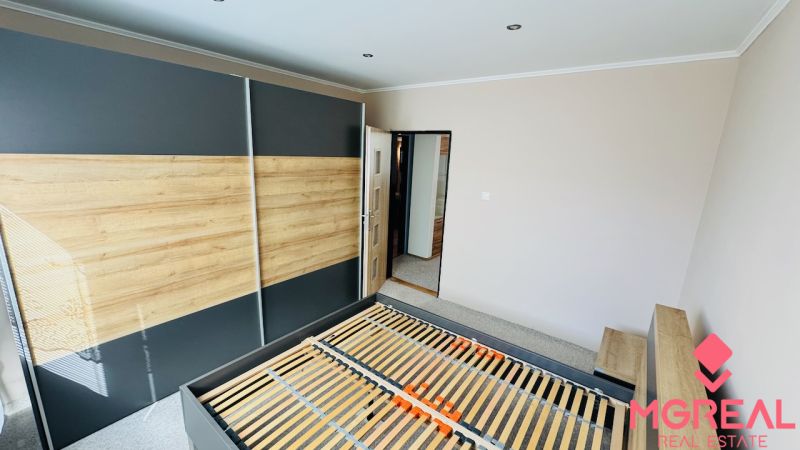 Bedroom with a built-in wardrobe and bed in a 3-room apartment with a wooden decor floor.