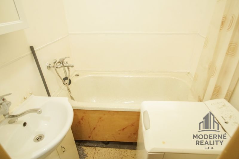 A bathroom in a 2-room apartment with a bathtub, sink, and washing machine.