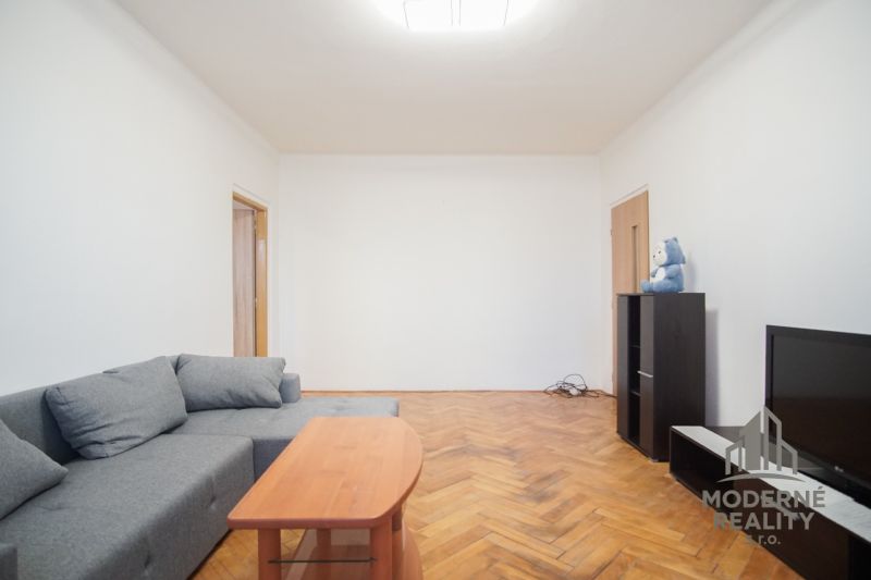Living room with a gray sofa and a floor with a wooden decor in a 2-room apartment.
