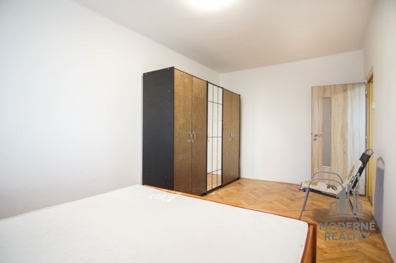 A bedroom with a wardrobe, a bed, and a floor with a wooden decor in a 2-room apartment.