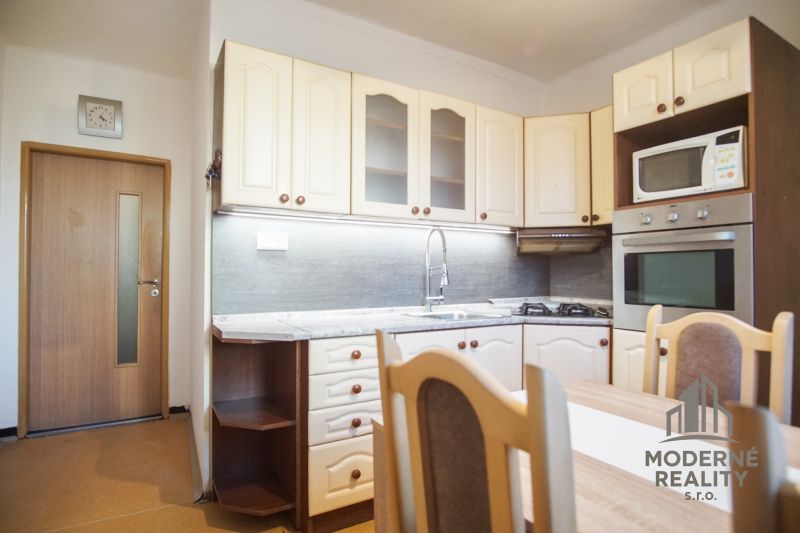 A kitchen in a 2-room apartment with built-in appliances and a dining table.