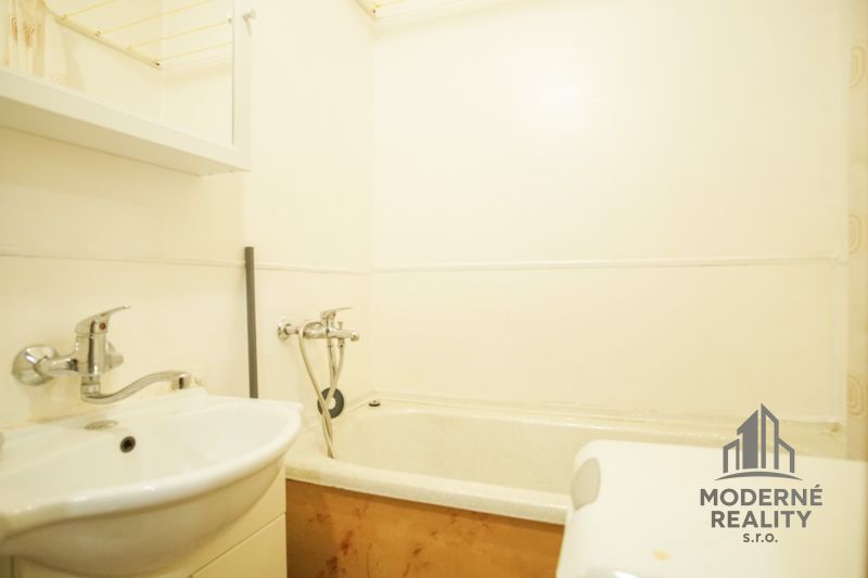 A bathroom with a bathtub and a sink in a 2-room apartment.