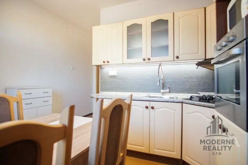 A kitchen unit in a 2-room apartment with a wood decor and a built-in oven.