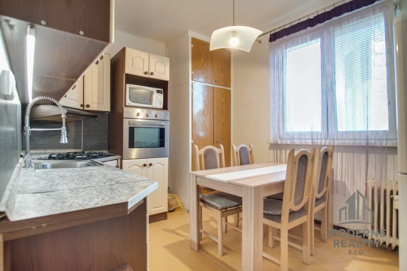Kitchen of a 2-room apartment with a dining table, kitchen unit, and a large window.