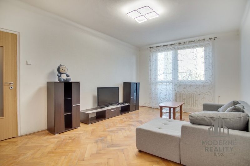 Living room in a two-room apartment with a wooden decor floor and a light interior.