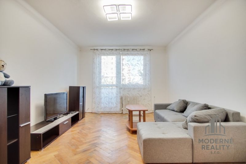 Living room with a sofa and TV in a two-room apartment, floor with wood decor.