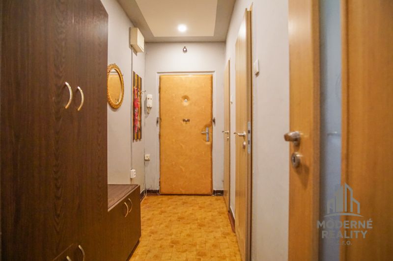A narrow hallway in a 2-room apartment with a wooden decor floor and wooden furniture.