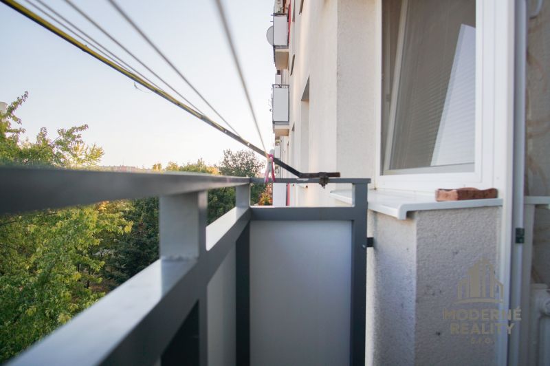 The balcony of a 2-room apartment in Nové Zámky with a view of green trees.
