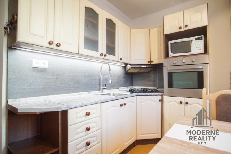 A kitchen in a 2-room apartment with white cabinets and built-in appliances.