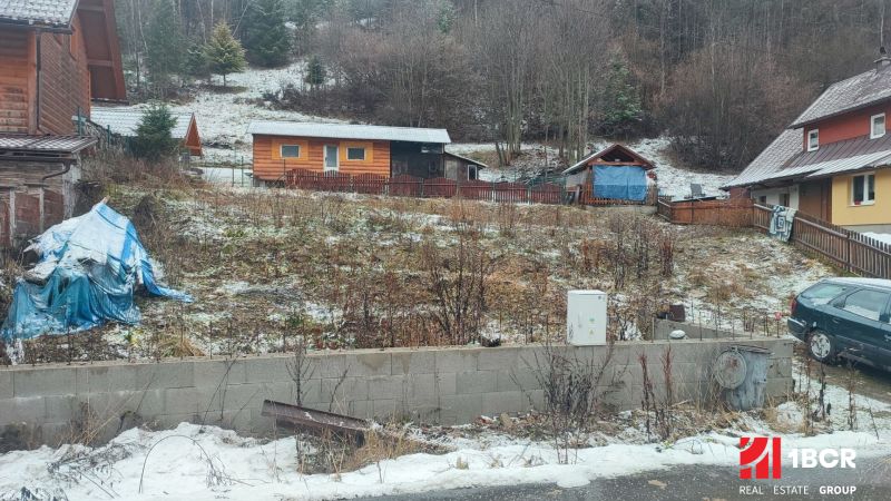 A snowy plot with a family house in Oščadnica surrounded by greenery and wooden structures.