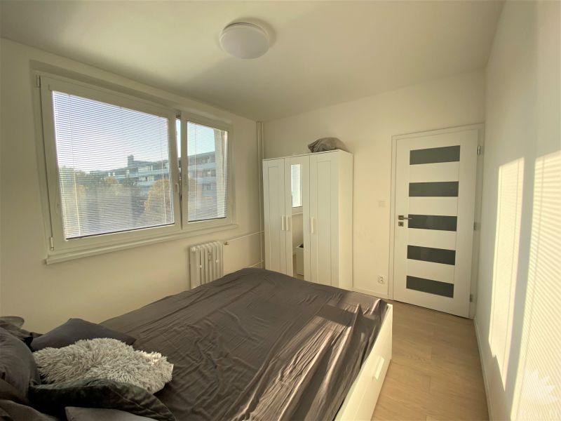 Bedroom in a 3-room apartment with a bed, wardrobe, window, and modern doors.