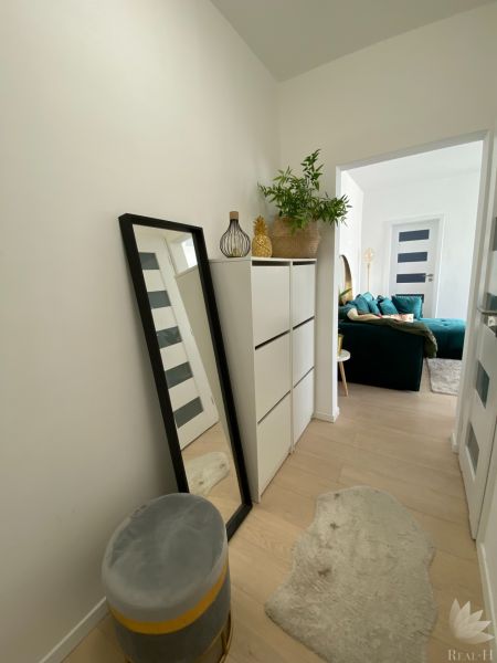 A hallway with white furniture, a mirror, and decorative items in a 3-room apartment.