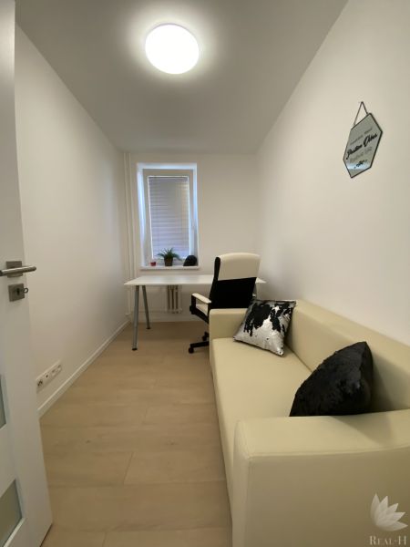 A narrow work corner in a 3-room apartment with a desk, chair, and sofa.