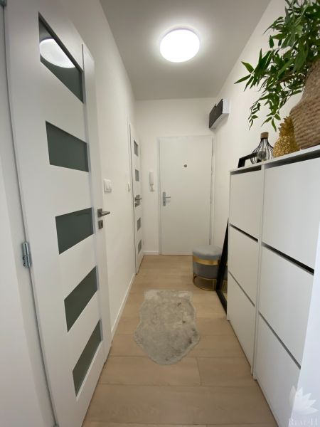 The entrance hall of a 3-room apartment with white furniture and wooden flooring.