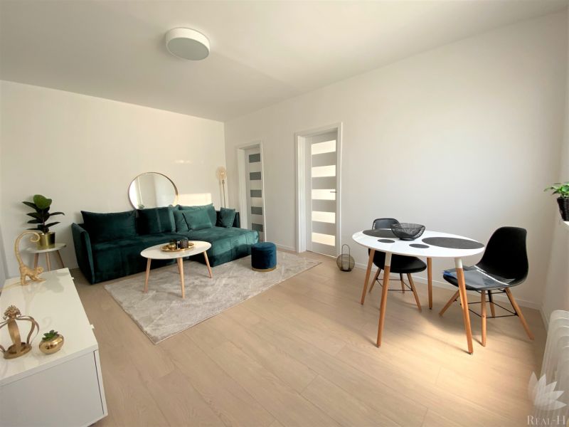 Living room in a three-room apartment with a sofa, table, and chairs.