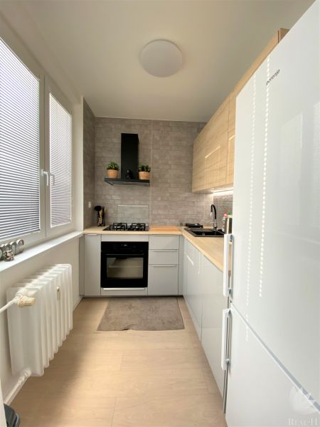 A kitchen in a 3-room apartment with white cabinets, a gas stove, and a radiator.