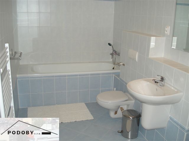 Bathroom in a 3-room apartment with a bathtub, sink, and toilet, blue and white tiles.