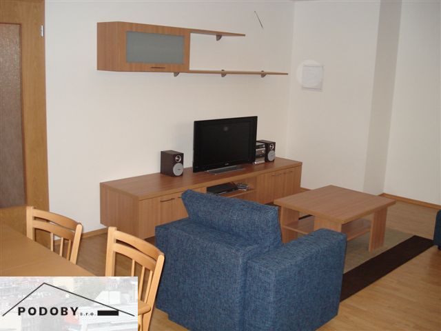 Living room with wood-patterned flooring, blue sofa, and television in a three-room apartment.