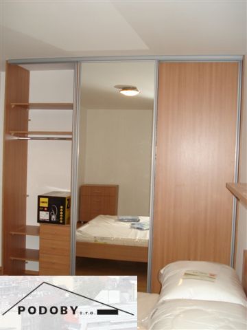 A bedroom with a wood-patterned floor and a built-in wardrobe in a 3-room apartment.