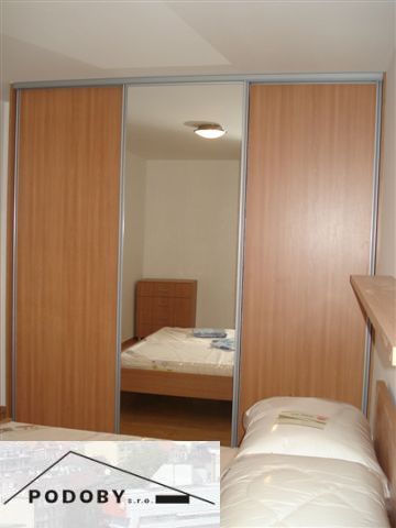 A bedroom in a 3-room apartment with a large built-in wardrobe and a floor with a wooden decor.
