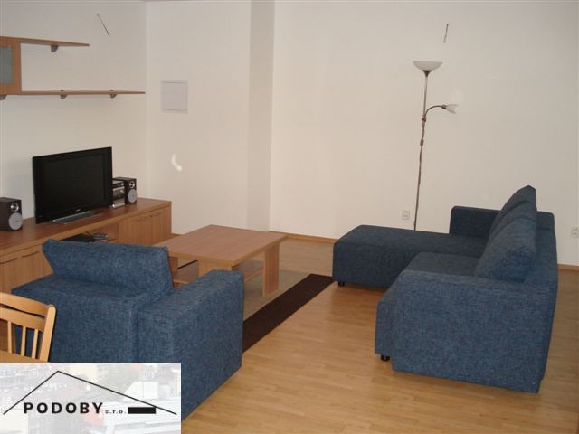 Living room in a 3-room apartment with a blue sofa and a wooden decor floor.