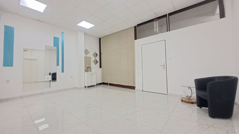Interior of commercial spaces with a chair, mirrors, and tiles with a white pattern.