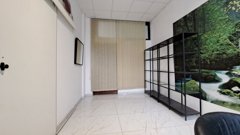 Small room with a shelf, white paneling, and green nature-themed wallpaper.
